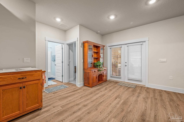 doorway to outside with visible vents, baseboards, a textured ceiling, french doors, and light wood-style floors