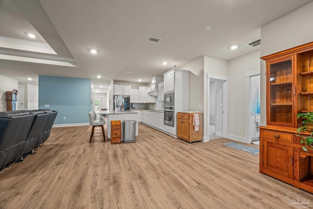 kitchen with stainless steel appliances, visible vents, open floor plan, a kitchen bar, and custom range hood