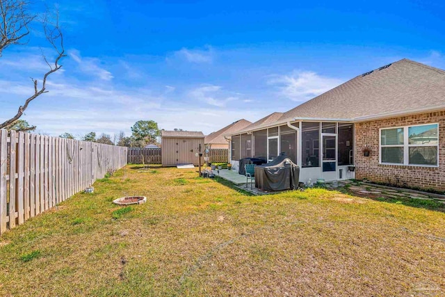 view of yard with a storage shed, an outdoor fire pit, a sunroom, a fenced backyard, and an outdoor structure