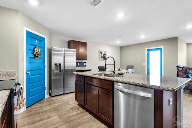 kitchen with light hardwood / wood-style floors, an island with sink, stainless steel appliances, and sink