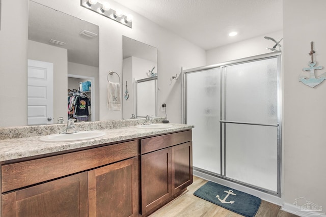 bathroom featuring vanity, a textured ceiling, hardwood / wood-style floors, and an enclosed shower