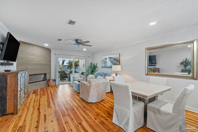 living area featuring ornamental molding, light wood-type flooring, and visible vents