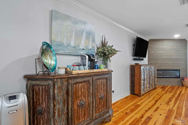 interior space with baseboards, light wood-style floors, visible vents, and crown molding