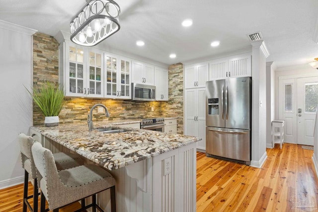 kitchen featuring stainless steel appliances, a sink, white cabinetry, visible vents, and light stone countertops