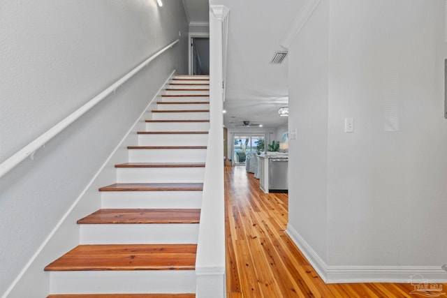 stairs with a ceiling fan, baseboards, visible vents, and wood finished floors