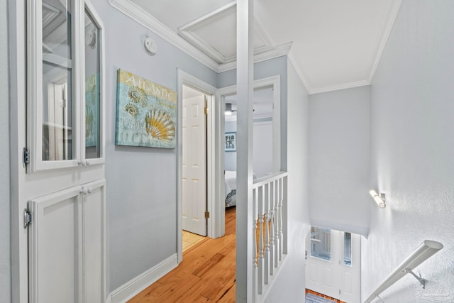 hallway featuring light wood-style flooring, baseboards, and crown molding