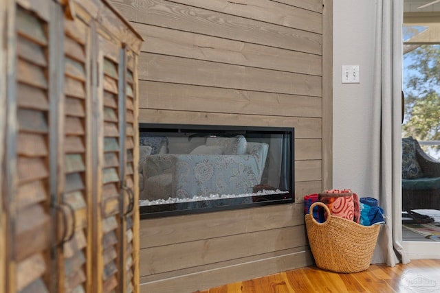 interior details with wooden walls, wood finished floors, and a glass covered fireplace