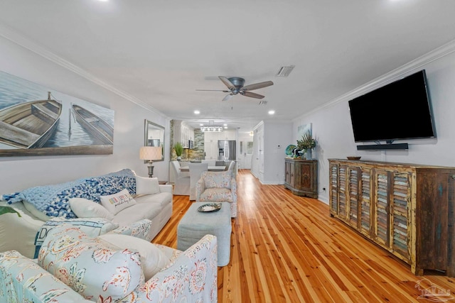 living room featuring visible vents, ornamental molding, ceiling fan, light wood-type flooring, and baseboards