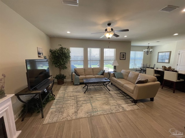 living area featuring recessed lighting, visible vents, wood finished floors, and ceiling fan with notable chandelier
