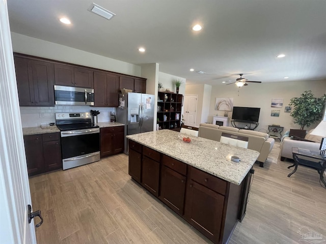 kitchen with a center island, light wood-style floors, ceiling fan, and stainless steel appliances
