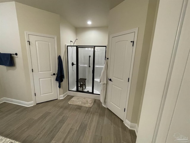 bathroom with baseboards, recessed lighting, a stall shower, and wood finished floors