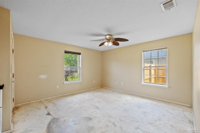 empty room with a textured ceiling, ceiling fan, and a wealth of natural light