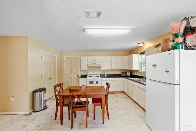 kitchen featuring a textured ceiling, white appliances, and sink