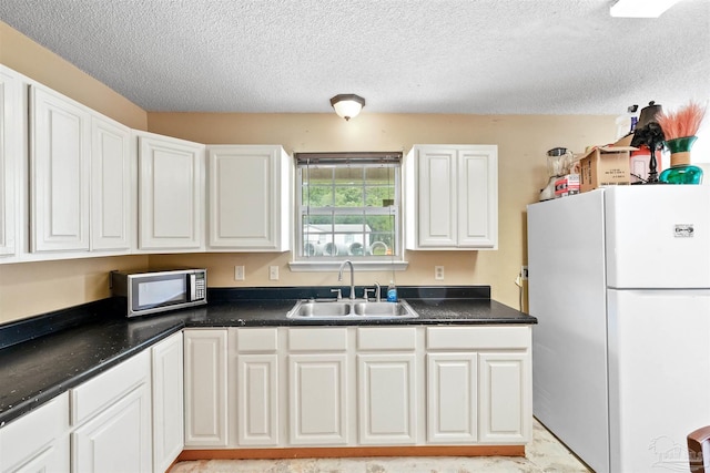 kitchen featuring white cabinets, a textured ceiling, white fridge, and sink