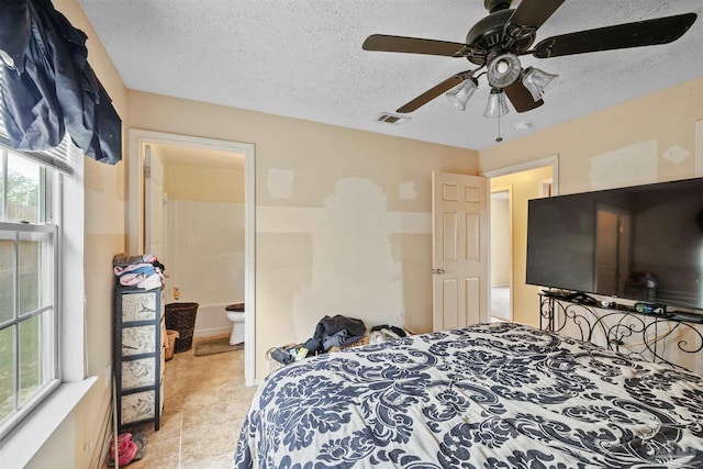 bedroom with a textured ceiling, ceiling fan, multiple windows, and ensuite bathroom