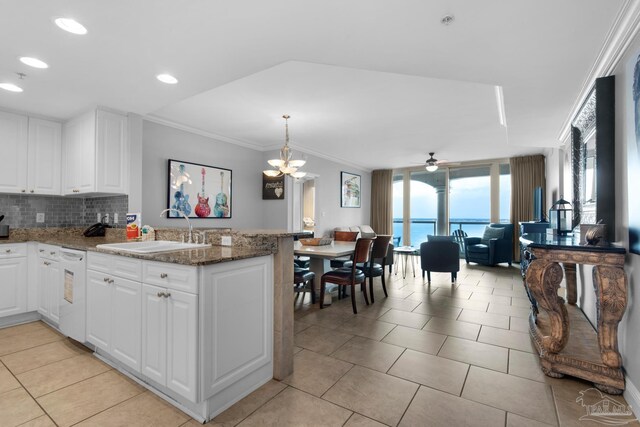 kitchen featuring dark stone counters, sink, decorative backsplash, crown molding, and a water view