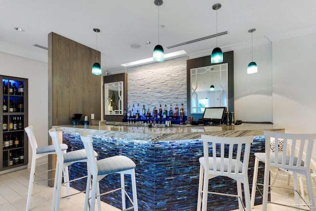 bar with hanging light fixtures, crown molding, and light stone counters