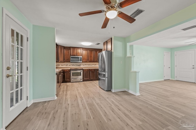 kitchen featuring visible vents, light wood-type flooring, decorative backsplash, and stainless steel appliances