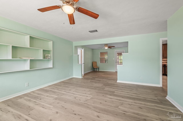 unfurnished living room with baseboards, ceiling fan, visible vents, and wood finished floors
