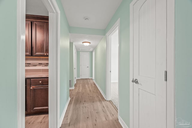 hall with baseboards and light wood-style flooring