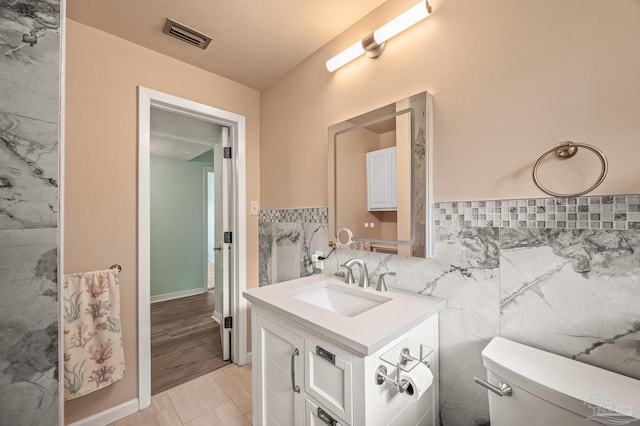 bathroom featuring toilet, tile walls, visible vents, and vanity