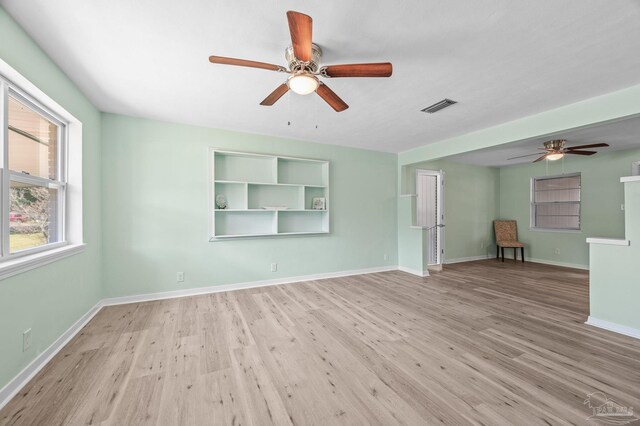 empty room featuring a ceiling fan, baseboards, visible vents, and wood finished floors