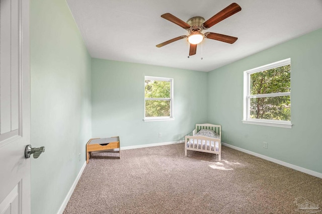 unfurnished room with carpet floors, a ceiling fan, and baseboards
