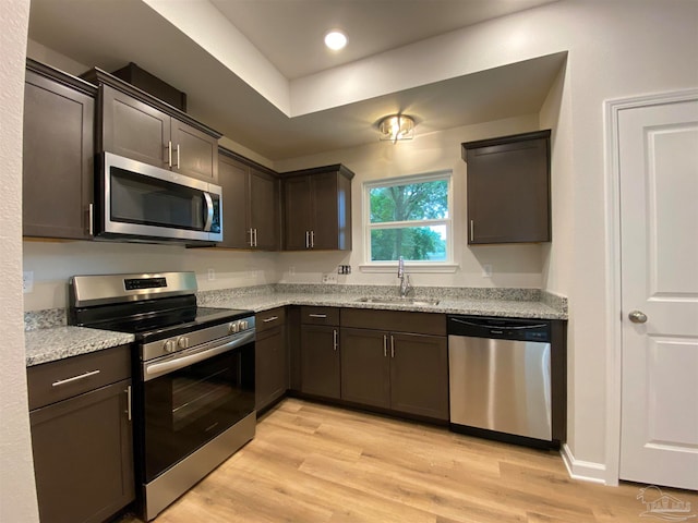 kitchen featuring stainless steel appliances, sink, light hardwood / wood-style flooring, and dark brown cabinetry