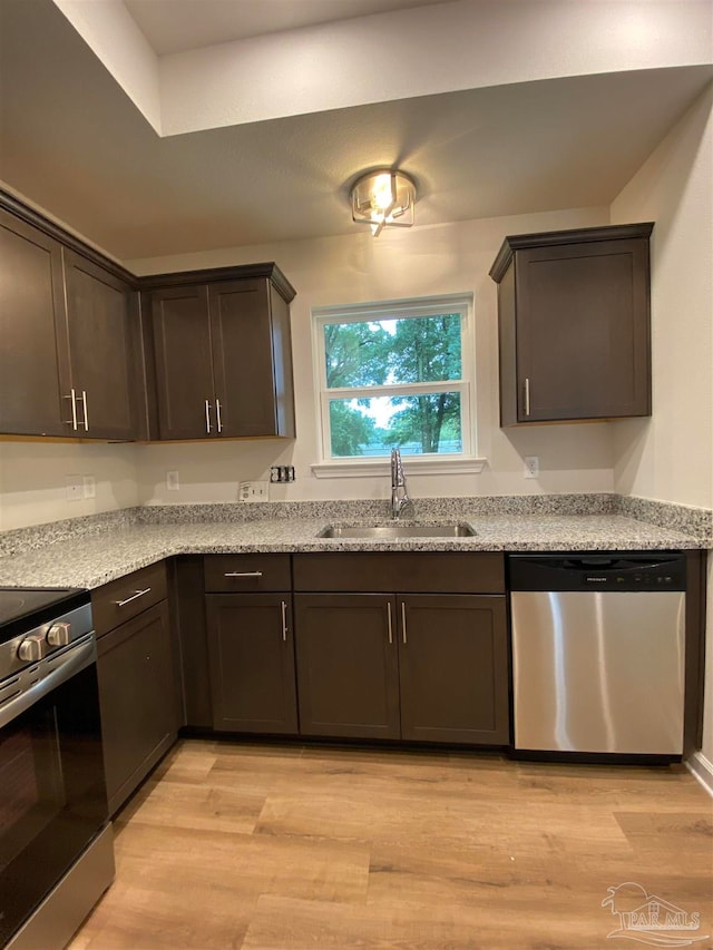 kitchen featuring light hardwood / wood-style floors, sink, light stone countertops, dark brown cabinets, and appliances with stainless steel finishes