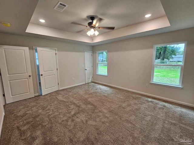 unfurnished room featuring ceiling fan, a raised ceiling, and carpet