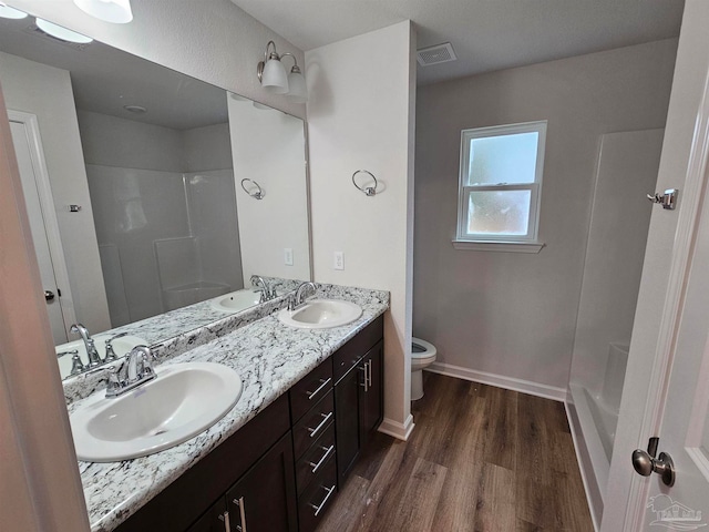 bathroom with wood-type flooring, toilet, vanity, and a shower