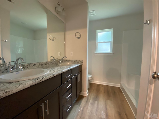 bathroom featuring walk in shower, wood-type flooring, toilet, and vanity