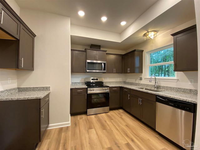 kitchen featuring light wood-type flooring, sink, dark brown cabinetry, and stainless steel appliances