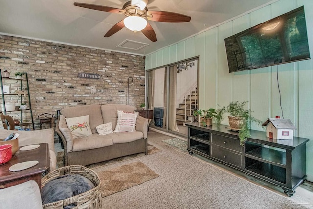 living room with ceiling fan, carpet floors, and brick wall