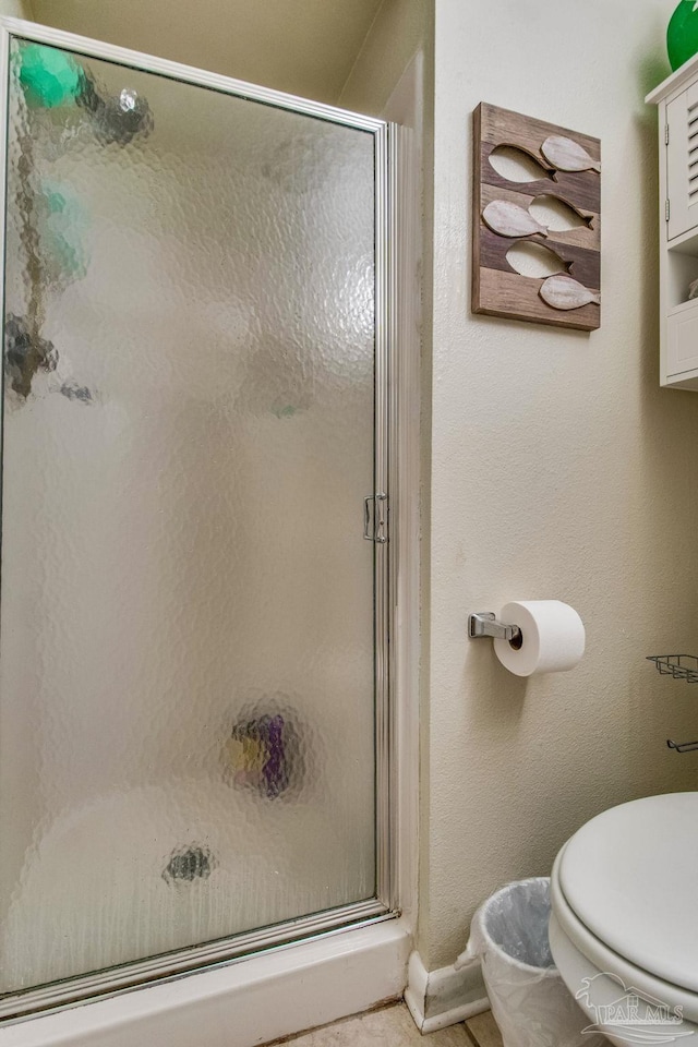 bathroom featuring toilet and a shower with shower door