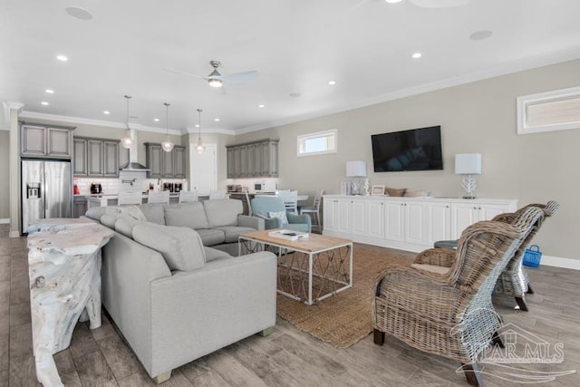 living room featuring light hardwood / wood-style floors, ornamental molding, and ceiling fan