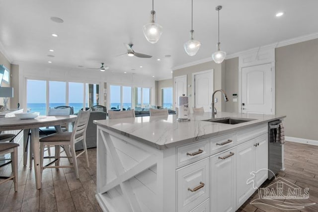 kitchen featuring wood-type flooring, ceiling fan, a water view, sink, and a kitchen island with sink