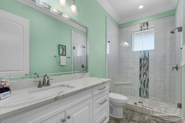 bathroom featuring a shower with shower door, vanity, crown molding, and toilet