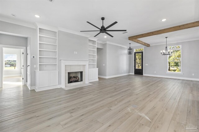 unfurnished living room with beam ceiling, light wood-type flooring, ceiling fan with notable chandelier, a tiled fireplace, and ornamental molding