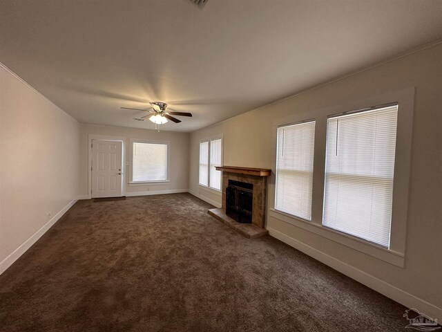 unfurnished living room featuring ceiling fan, dark carpet, and a tiled fireplace