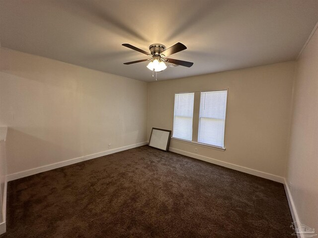 spare room featuring dark colored carpet and ceiling fan