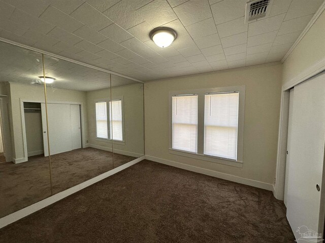 unfurnished bedroom featuring dark carpet and ornamental molding