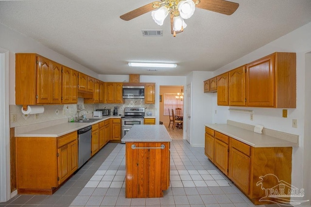 kitchen featuring ceiling fan, appliances with stainless steel finishes, light tile patterned floors, a kitchen island, and sink