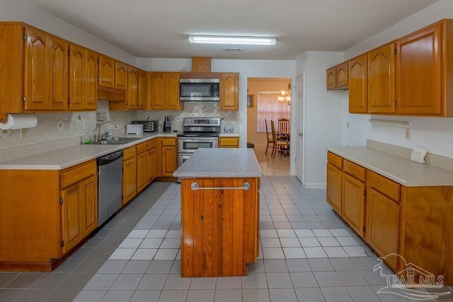 kitchen with backsplash, light tile patterned flooring, stainless steel appliances, sink, and a center island