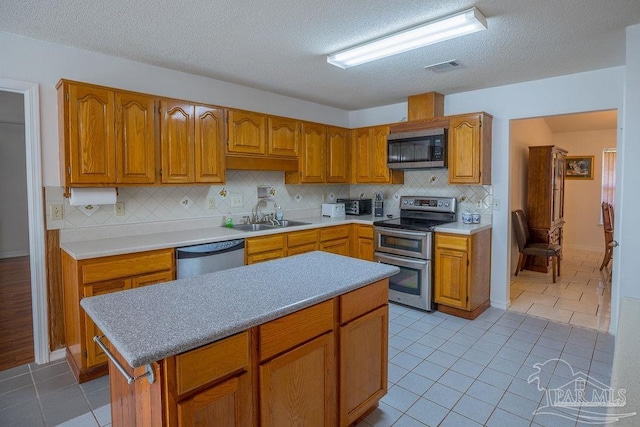 kitchen with a textured ceiling, tasteful backsplash, stainless steel appliances, and sink