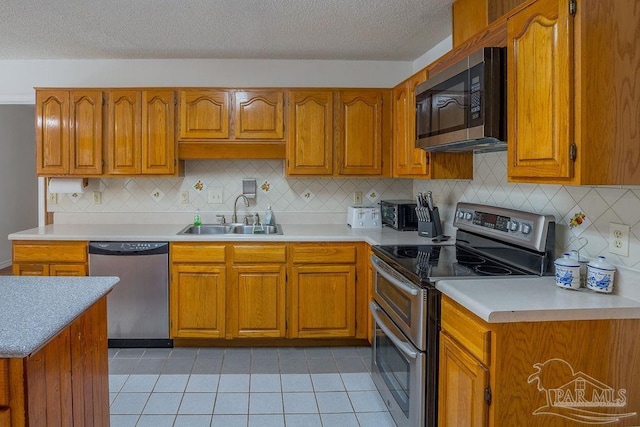 kitchen featuring appliances with stainless steel finishes, sink, light tile patterned floors, and backsplash