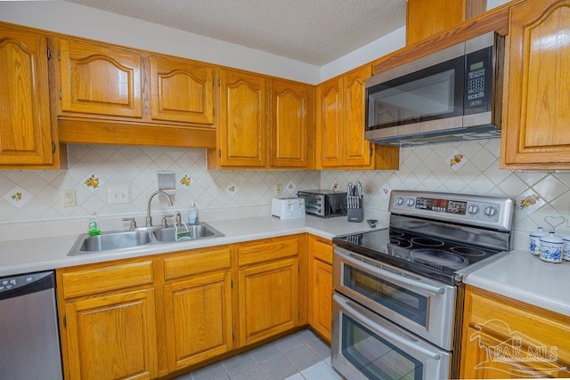 kitchen with tasteful backsplash, appliances with stainless steel finishes, sink, a textured ceiling, and light tile patterned floors