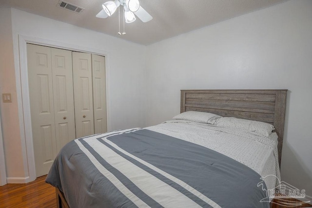 bedroom with a closet, dark wood-type flooring, and ceiling fan