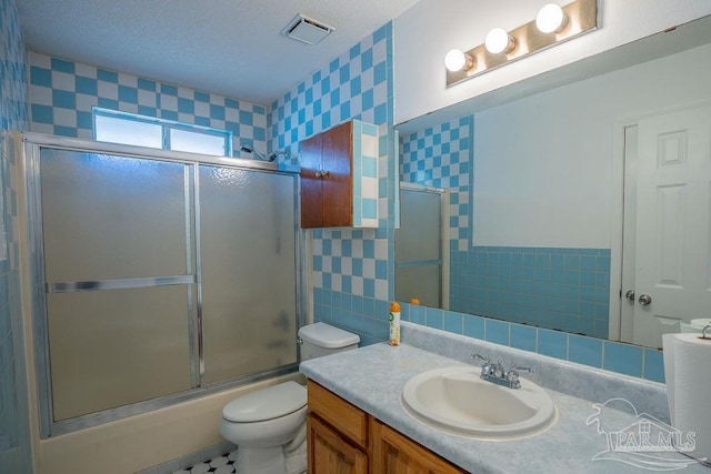 full bathroom featuring toilet, shower / bath combination with glass door, vanity, and tile walls