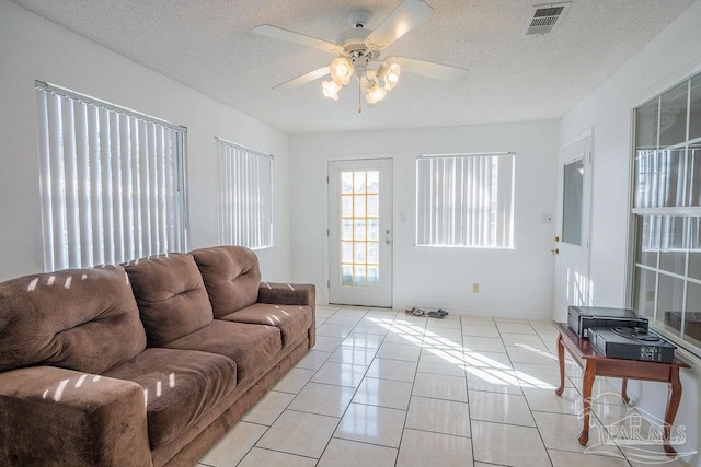 tiled living room featuring ceiling fan and a textured ceiling